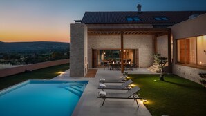 Una casa moderna con piscina, mobiliario de exterior y vistas al paisaje.