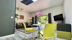 Una sala moderna con comedor, un televisor de pantalla plana en la pared y un ventanal que ofrece vistas al exterior.