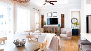 Ein geräumiges Wohnzimmer mit einer großen Couch, einem Holzespeisetisch und einem an der Wand befestigten Fernseher.