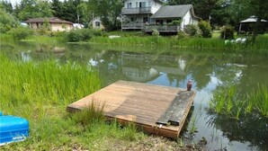 A wooden dock extending into a pond with surrounding greenery and houses in the background. - Canal front Island Escape for the family! Dog-Friendly with private Dock  (Ocean Shores)