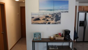 A kitchen with a refrigerator, a coffee maker, and a small table with a picture frame and a book. - Canal front Island Escape for the family! Dog-Friendly with private Dock  (Ocean Shores)