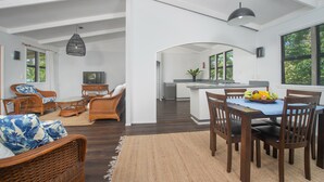 A spacious living area with a dining table, chairs, and a television.