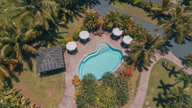 Luchtbeeld van een resort met een zwembad, ligbedden en palmbomen.