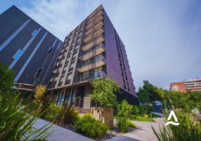 A modern high-rise building with multiple balconies and a landscaped courtyard.