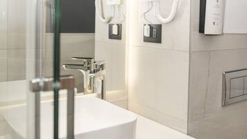 Une salle de bain moderne avec une douche à parois de verre, un lavabo blanc et un porte-serviettes.