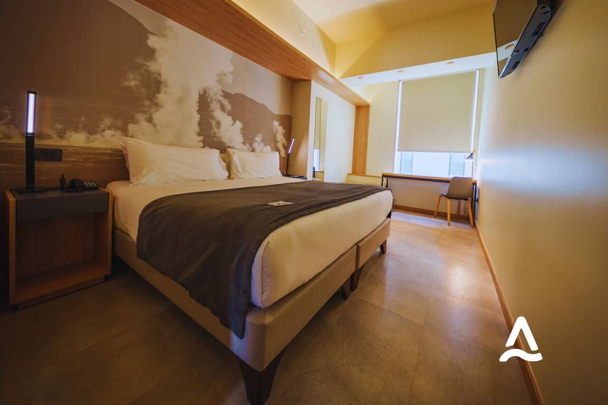 Een moderne slaapkamer met een groot bed, nachtkastjes, een bureau en een stoel.