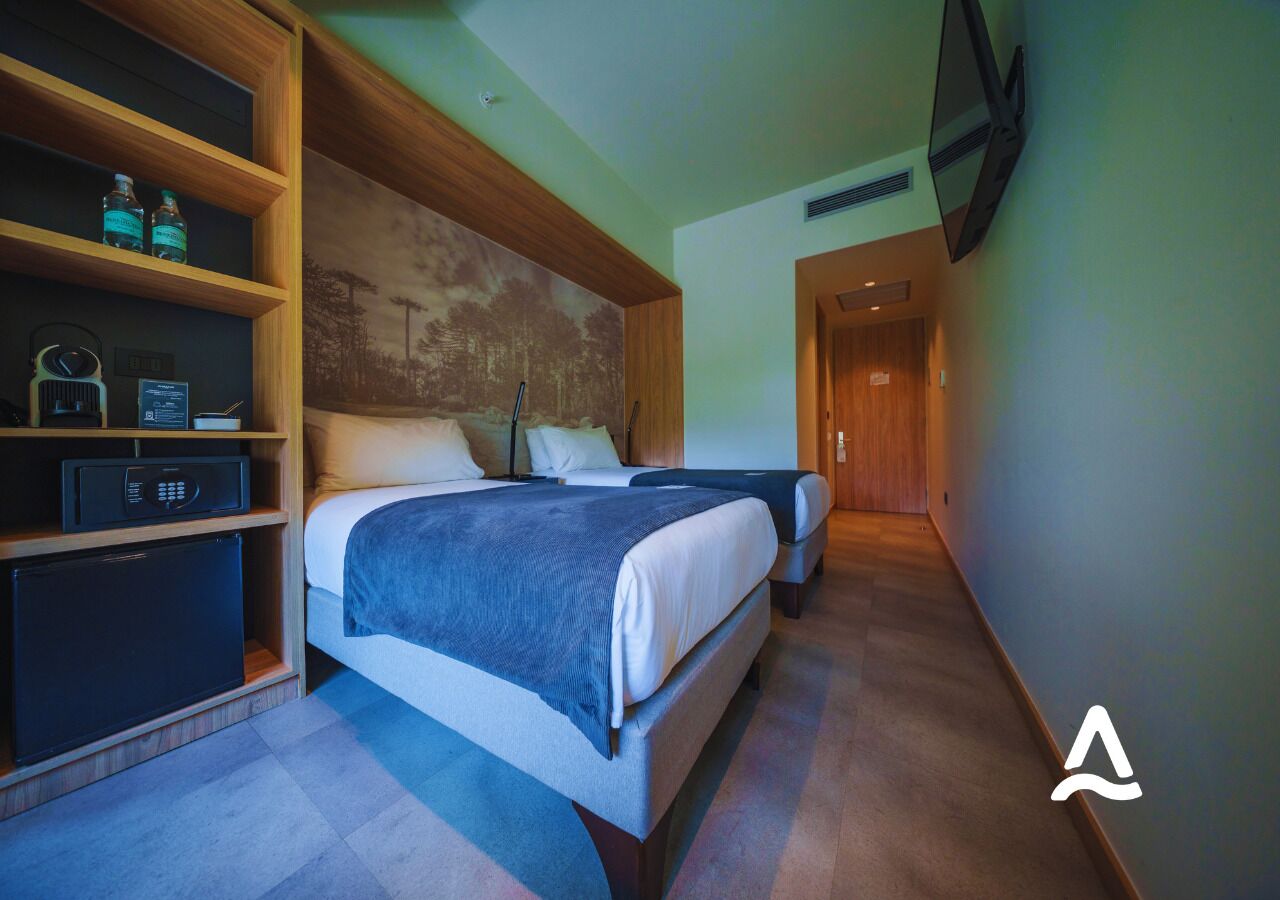 Una habitación de hotel con dos camas, un armario empotrado, microondas y un refrigerador pequeño.