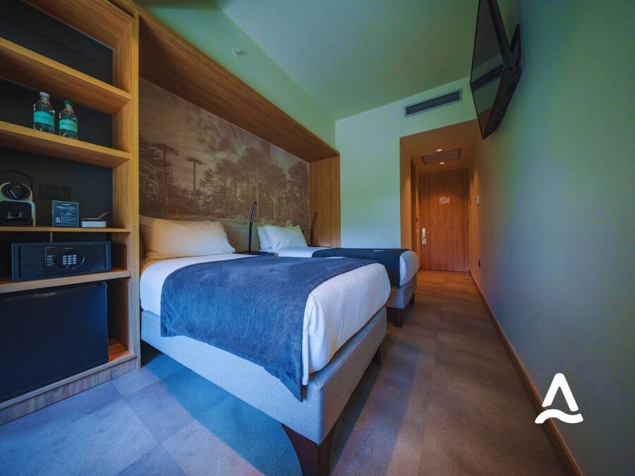 Una habitación de hotel con dos camas, un armario empotrado, microondas y un refrigerador pequeño.