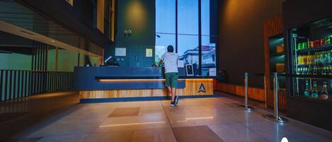 A modern reception area with a counter, a large window, and a bar area with bottles.