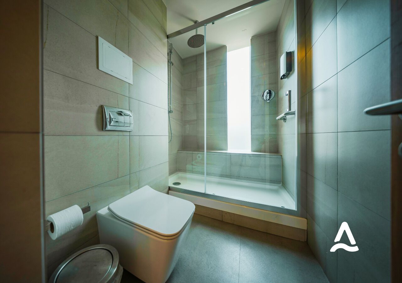 Un baño moderno con inodoro, cabina de ducha y puerta de vidrio.