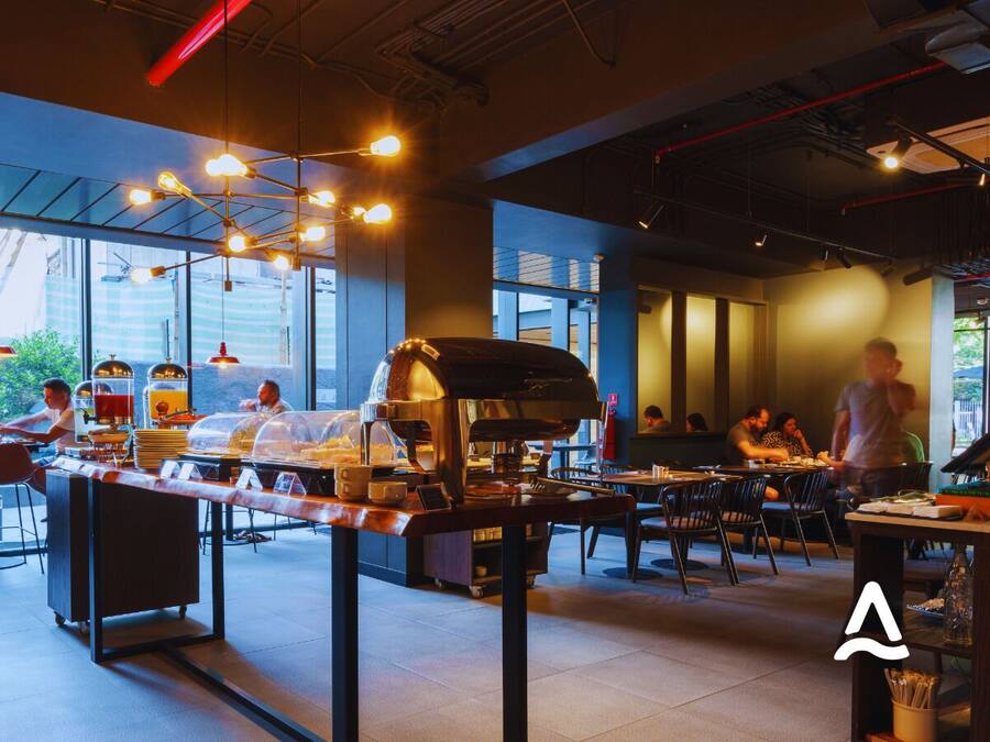 Una cafetería moderna con barra de café, zona de estar y amplios ventanales.