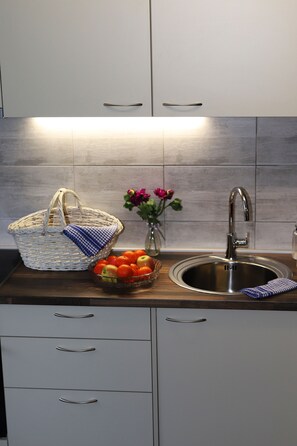 Een keuken met een roestvrijstalen spoelbak, een rieten mand, een fruitschaal en een vaas met bloemen.