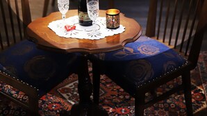 Una mesa con una botella y dos vasos sobre un mantel de encaje.