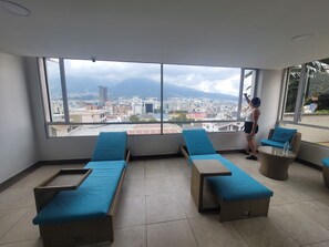 A balcony with wicker lounge chairs and a large window offering a city view. - 500 Excellent panoramic view, olympic stadium, park, mountain swimming pool (Quito)