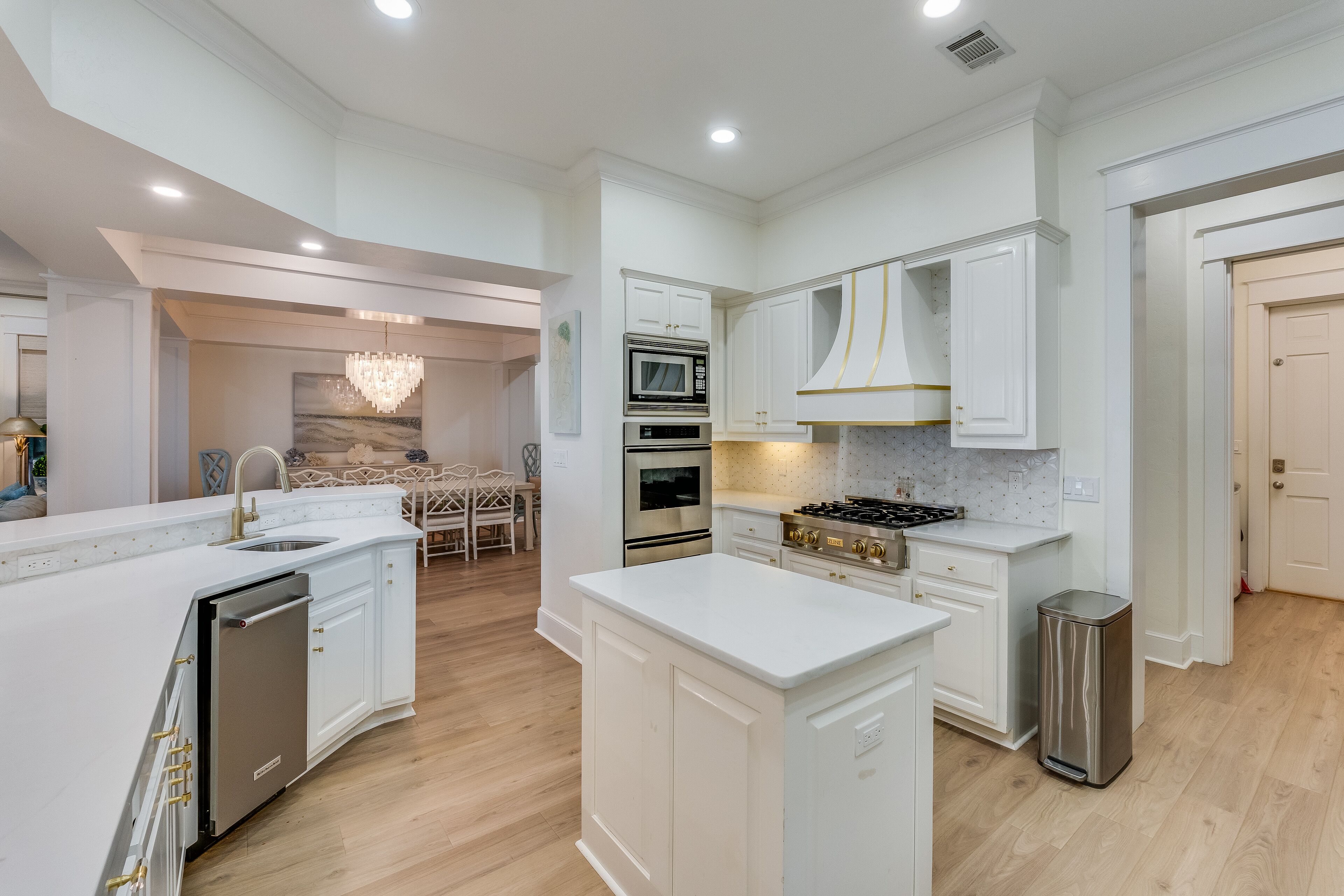 A modern kitchen with white cabinetry, stainless steel appliances, and a central island.