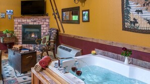 A room with a fireplace, a large tub, and a television. - Eureka Sunset Cabins (Eureka Springs)