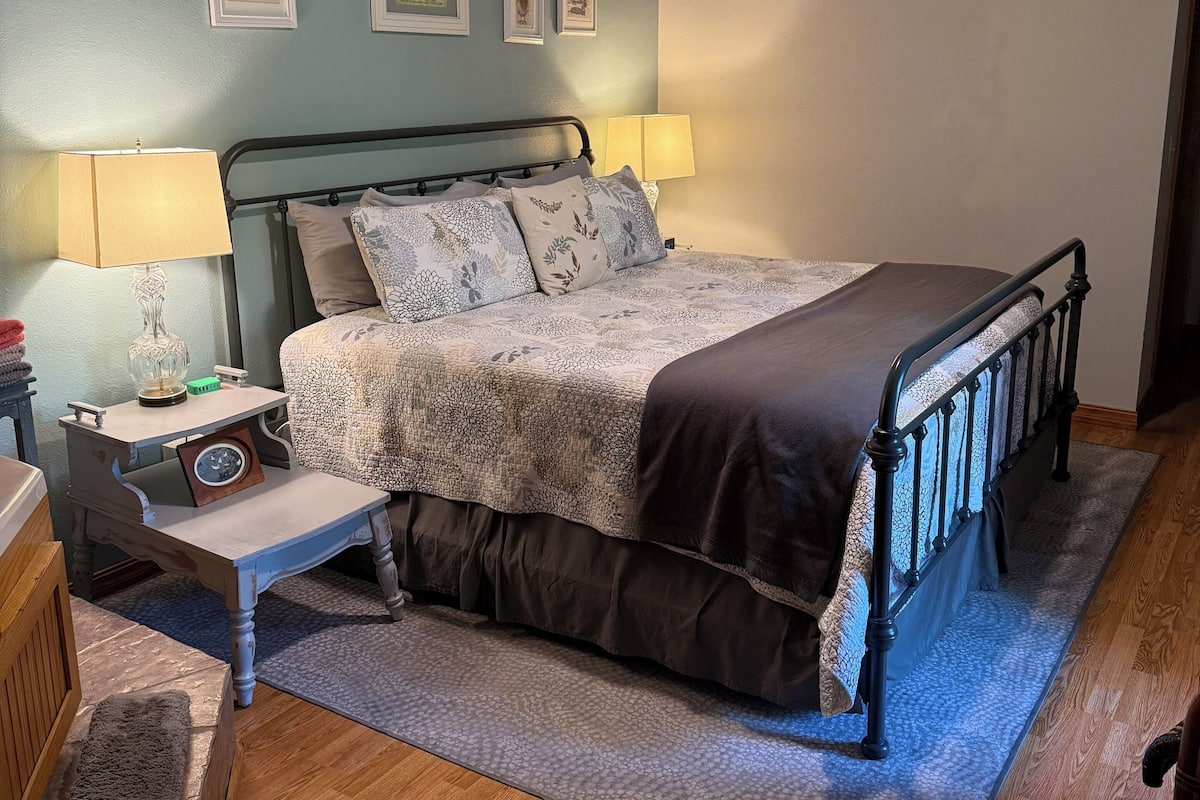 A bedroom with a bed, bedside tables, a ceiling fan, and framed pictures on the wall.