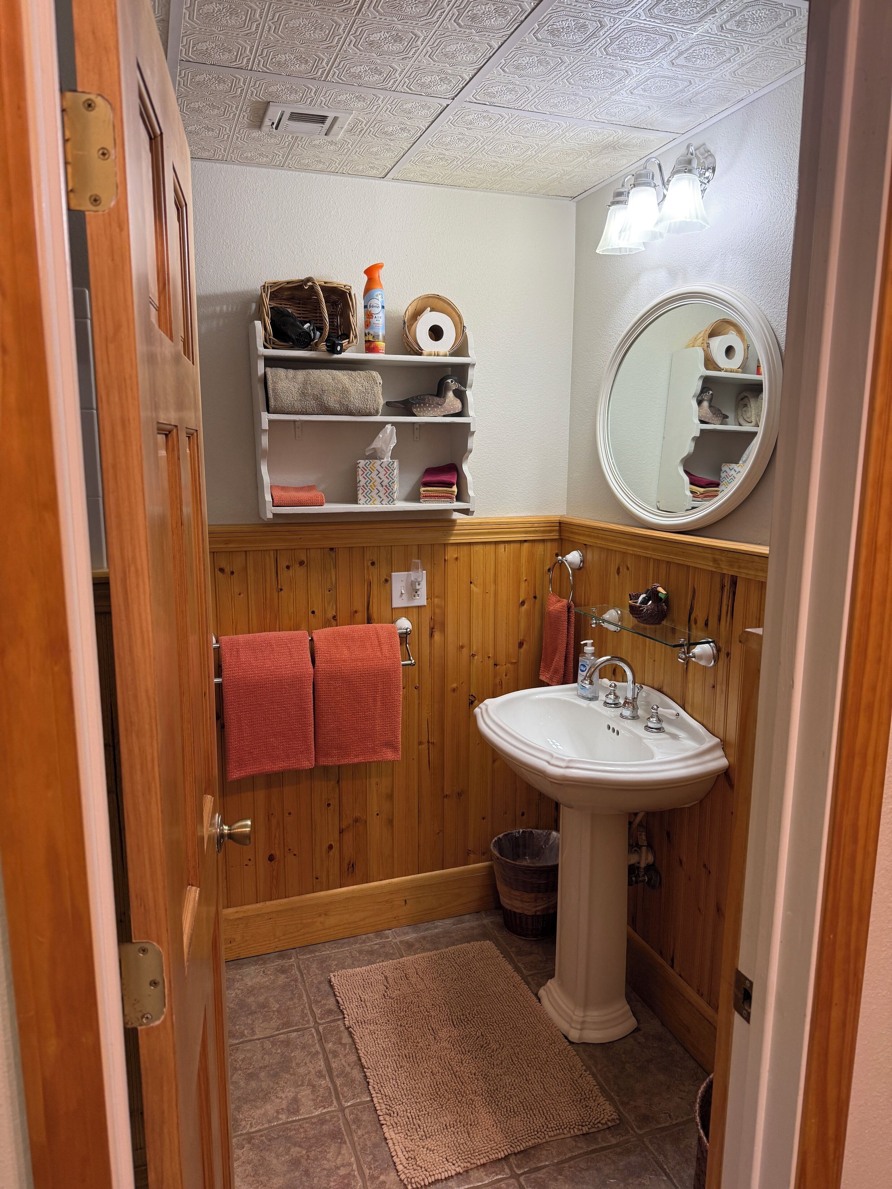 Un baño con paneles de madera, un lavamanos blanco y un espejo con iluminación.