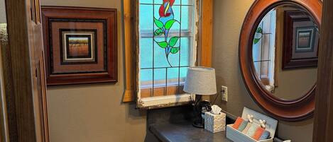 A bathroom with a white toilet, a sink with a mirror, a stained glass window, and a small framed picture on the wall.
