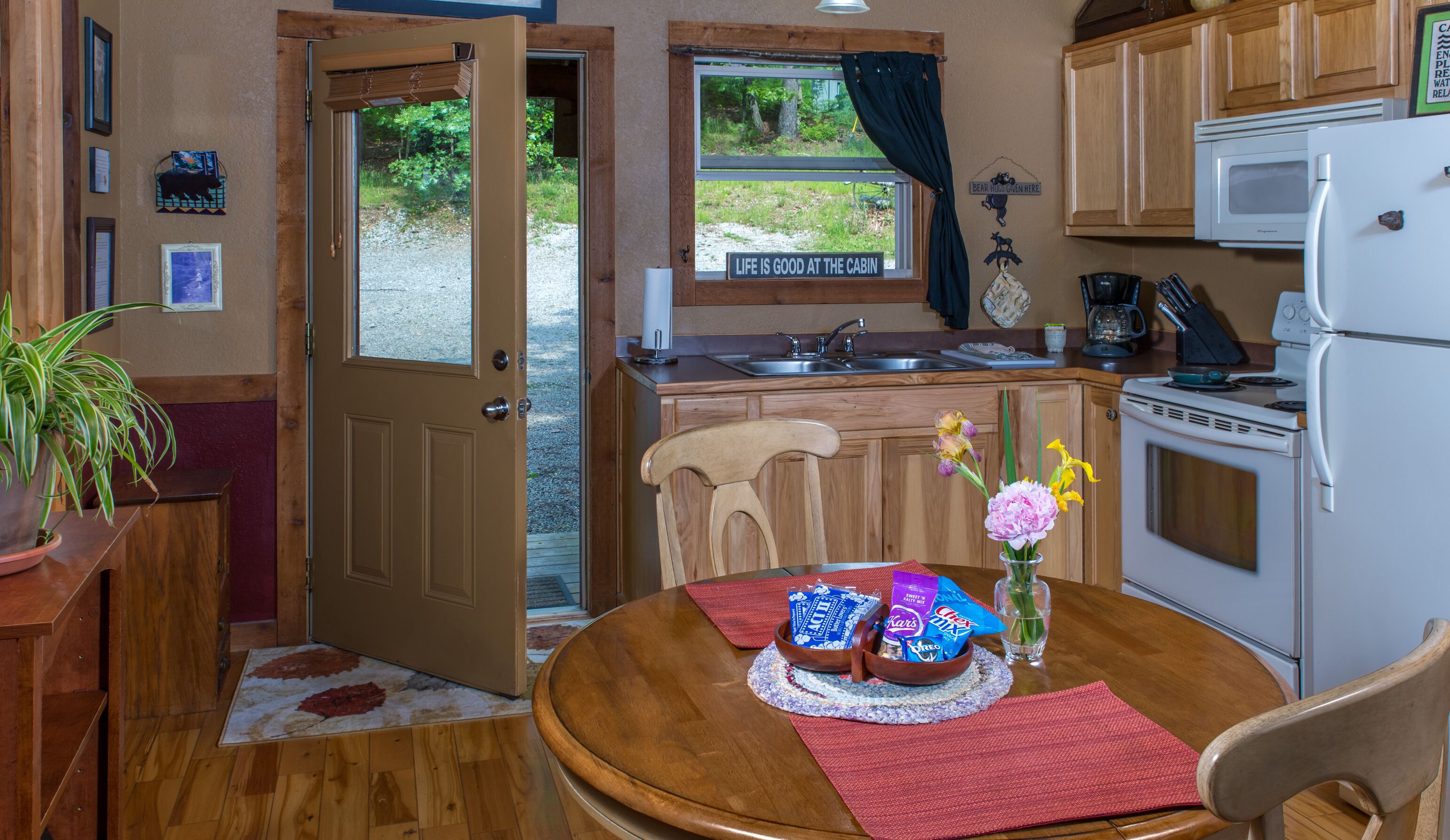 Une cuisine compacte avec des meubles en bois, un four à micro-ondes et une cuisinière. On peut voir une table à manger avec un set de table et un vase de fleurs.