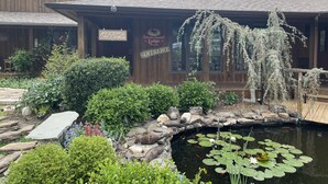 A wooden lodge with a pond, lily pads, and a sign reading "Eureka Sunset Lodge." - Eureka Sunset Cabins (Eureka Springs)