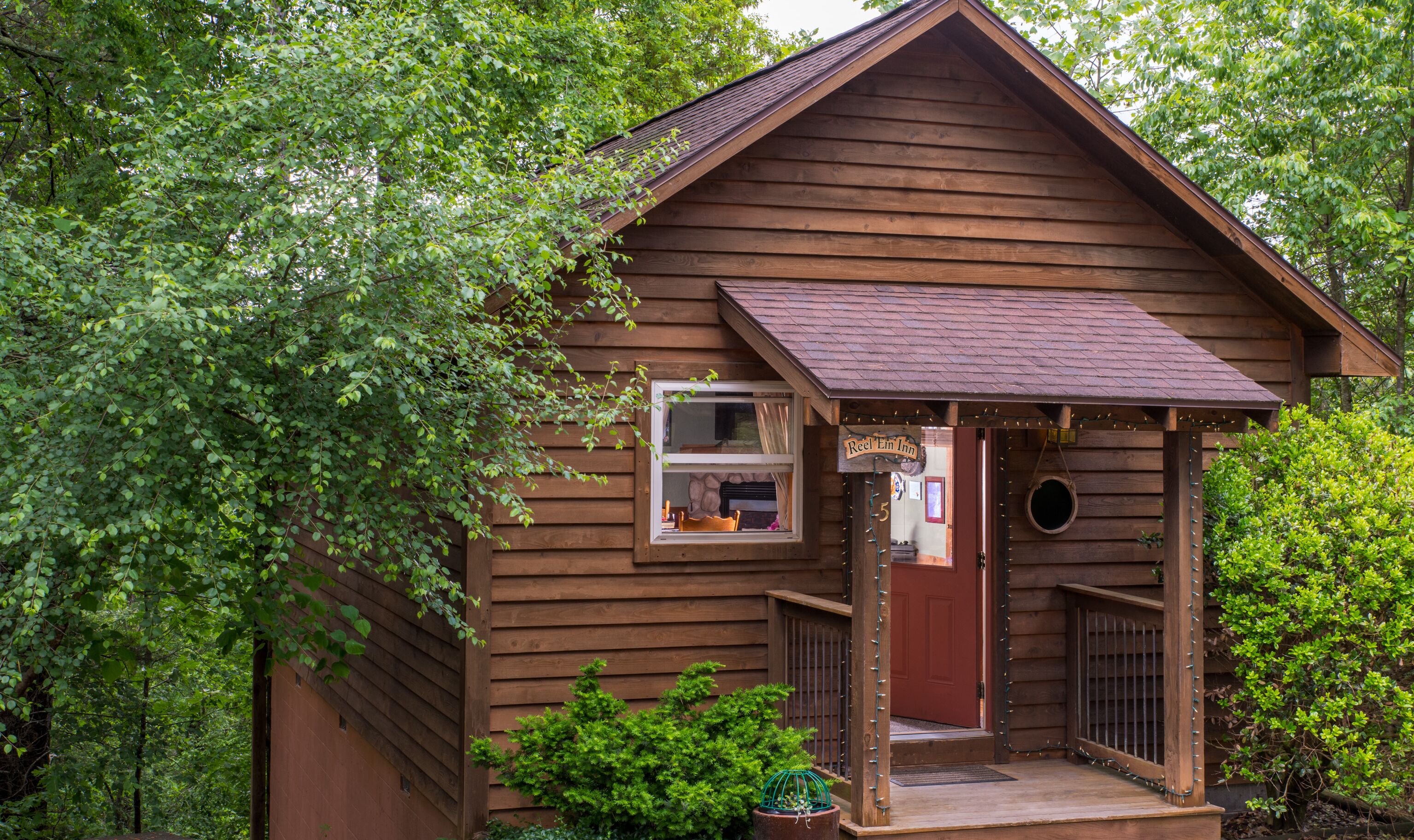 Une cabane en bois avec un toit à deux versants, un petit porche et une fenêtre.
