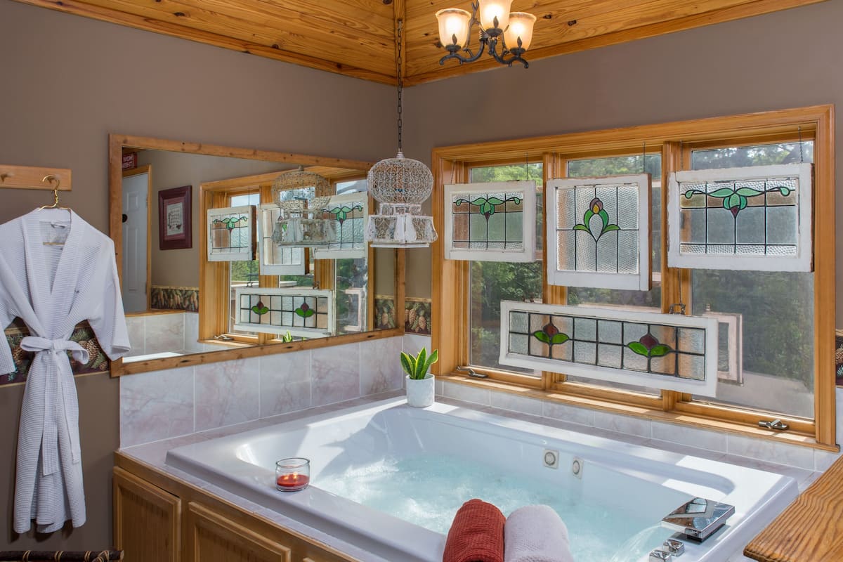 A bathroom with a large bathtub, wooden ceiling, and decorative stained glass windows.