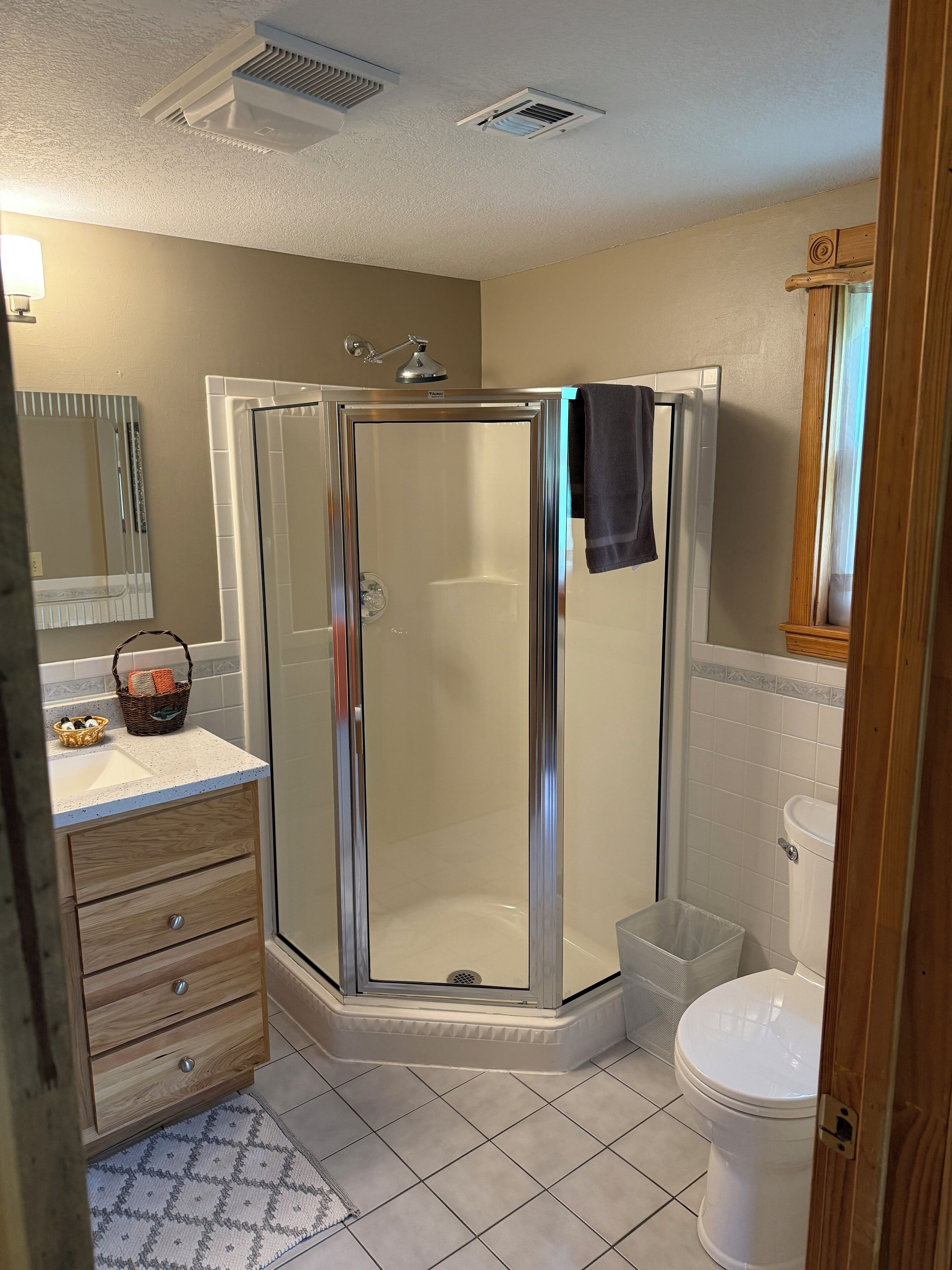 A modern bathroom with a glass-enclosed shower, a wooden vanity with a sink, and a toilet.