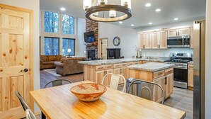 Een moderne keuken met houten kasten, een groot eiland en een eetgedeelte met een houten tafel en stoelen.