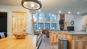 Een moderne keuken met houten kastjes, een groot eiland en een eethoek met een houten tafel.