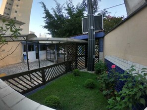 A courtyard with a covered seating area, a small garden, and a building with blue-tiled walls.