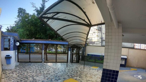 Un espace extérieur abrité doté d’un sol carrelé, d’un chemin accessible aux personnes à mobilité réduite et d’un mur recouvert de carreaux bleus.