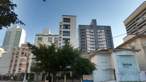 Une vue de rue avec des immeubles, un arbre et une poubelle bleue.
