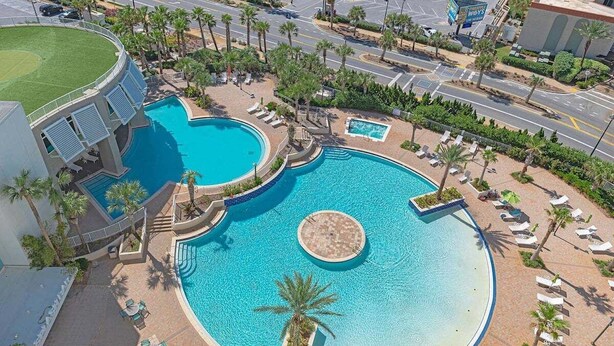 A large outdoor swimming pool with multiple sections and lounge chairs around it.