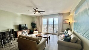 A living room with a sofa, armchair, television, and a ceiling fan.
