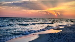 A beach with waves and a sunset.