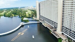 A high-rise hotel with multiple floors, a waterfront promenade, and a dock extending into a body of water.