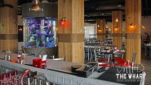 A restaurant interior with wooden pillars, a central aquarium, and a bar area.