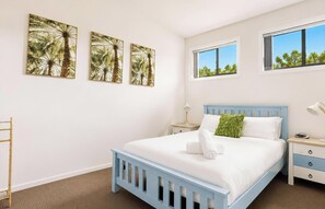 Ein Schlafzimmer mit Bett, Nachttischen, einem Fenster und Wandbildern.