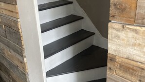 Een trap met zwarte treden en witte wanden, die naar een houten muur leidt.