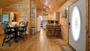 Ambiente in legno con zona pranzo, cucina e una grande finestra.