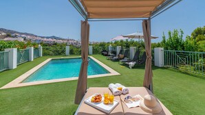 Ein Poolbereich mit Frühstückstisch, Pool und Liegestühlen.