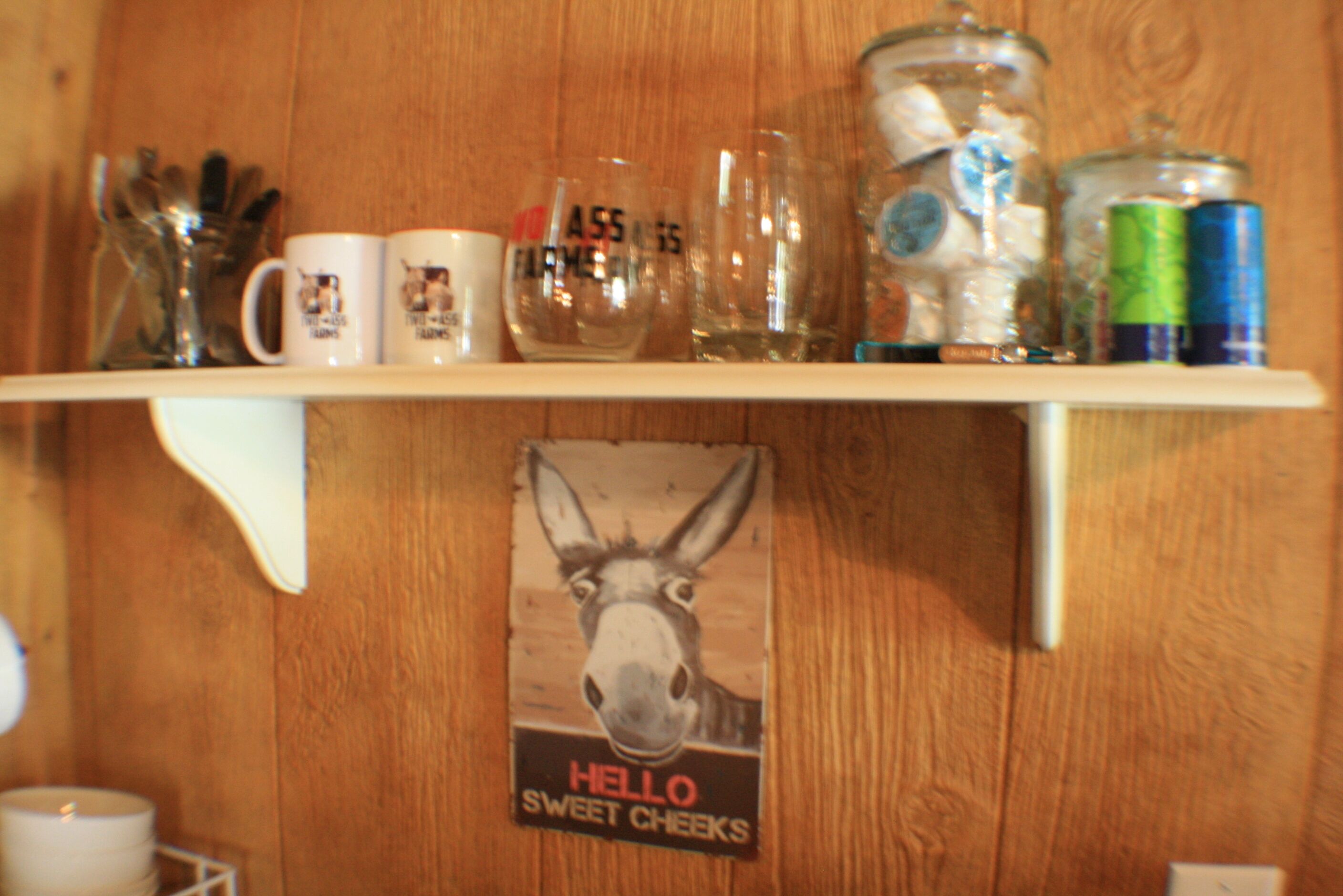 Une étagère avec des tasses, des verres et une affiche représentant un âne.
