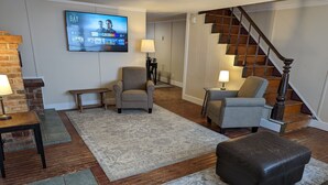 Ein Wohnzimmer mit einem an der Wand befestigten Flachbildfernseher, einer Treppe und einer Kombination aus Teppich- und Holzdielenböden.