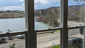 Blick aus einem Fenster auf einen Fluss, eine Straße mit Fahrzeugen und eine Brücke.