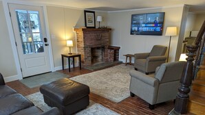 Ein Wohnzimmer mit Kamin, Ledersofa, Sessel und Fernseher, der die Serie 'Billions' zeigt.