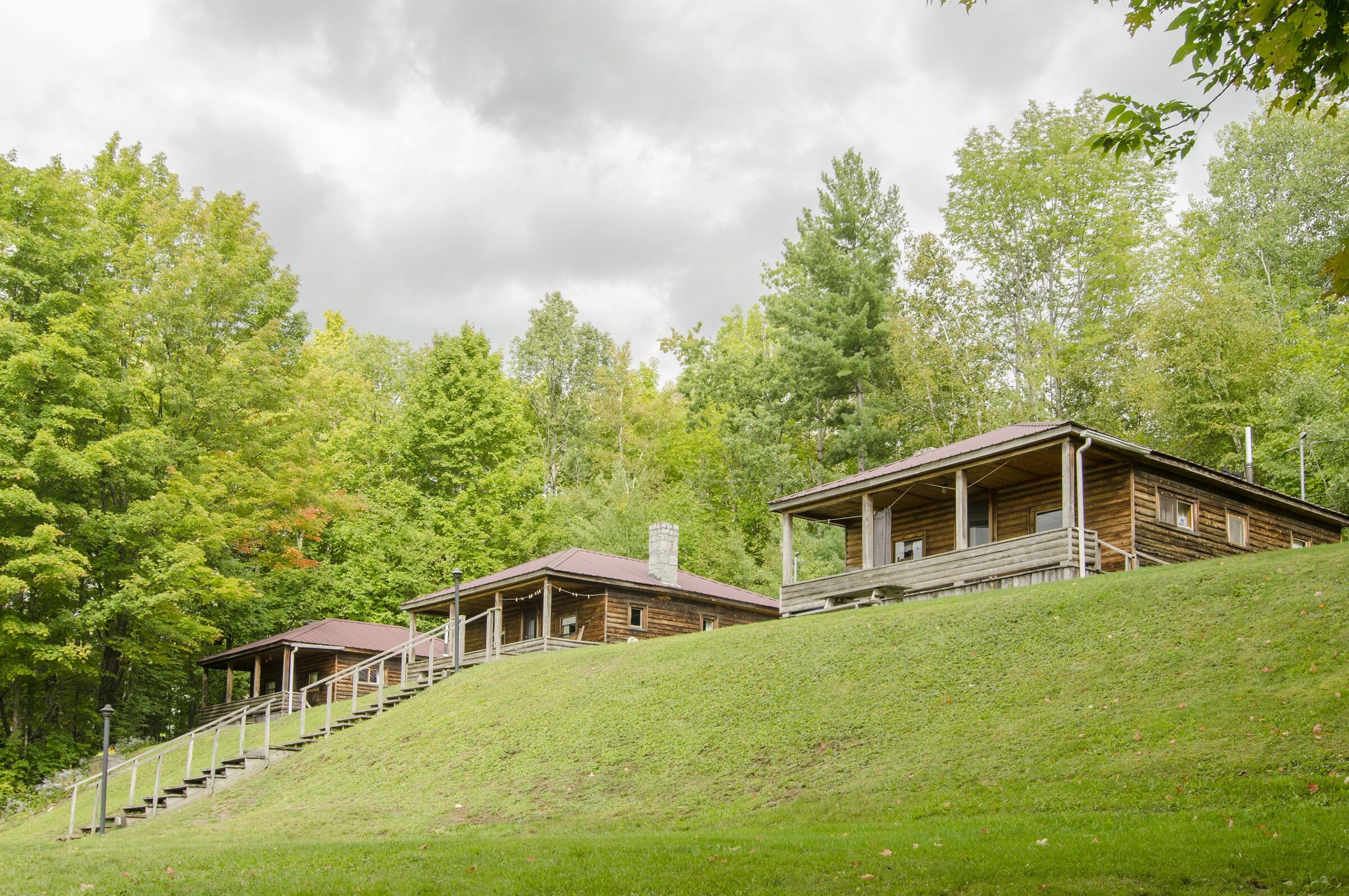 A rustic cabin with a wooden exterior, a porch, and a staircase leading up to the entrance.