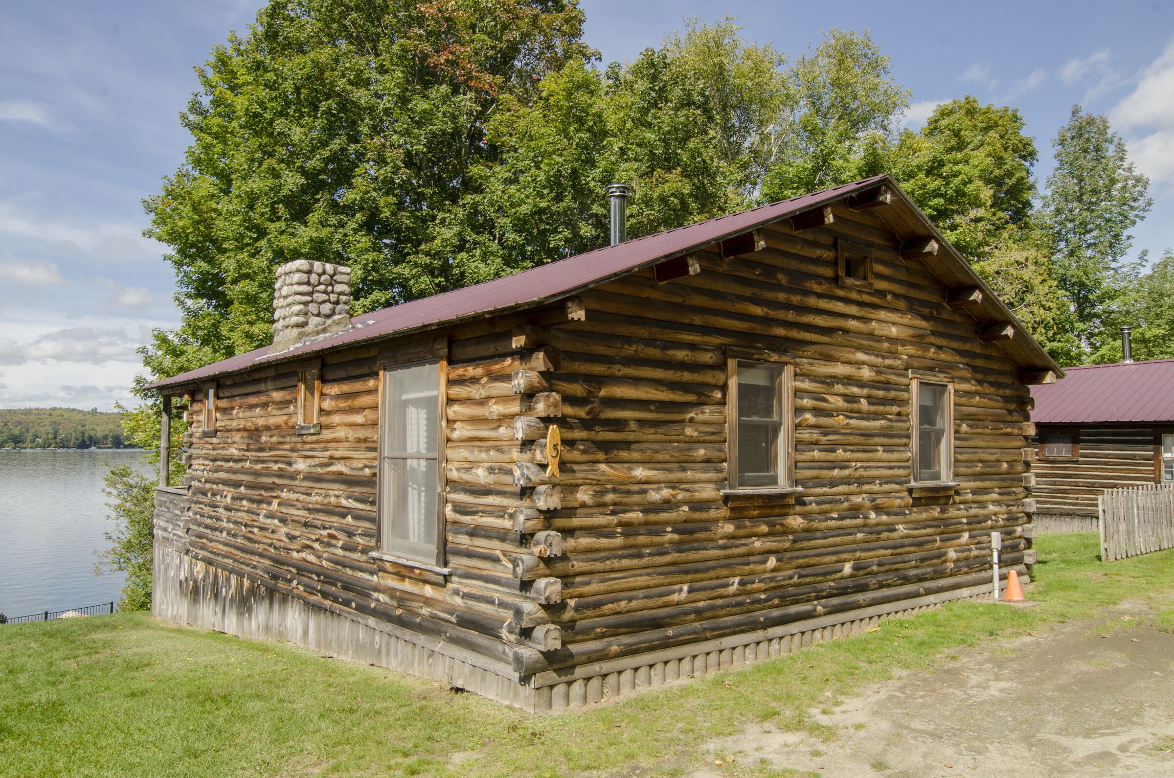 A log cabin with a chimney, windows, and a small porch.