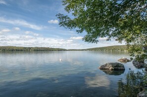A calm lake with clear water, surrounded by trees and hills. - Mountain Lake Cottages (Orleans)