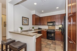 Una cucina moderna con mobili in legno, un piano di lavoro in granito, forno integrato, microonde e frigorifero.